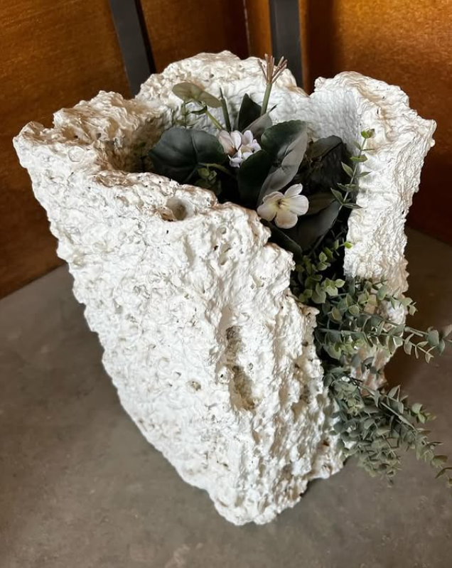 White textured planter with small white flowers and greenery